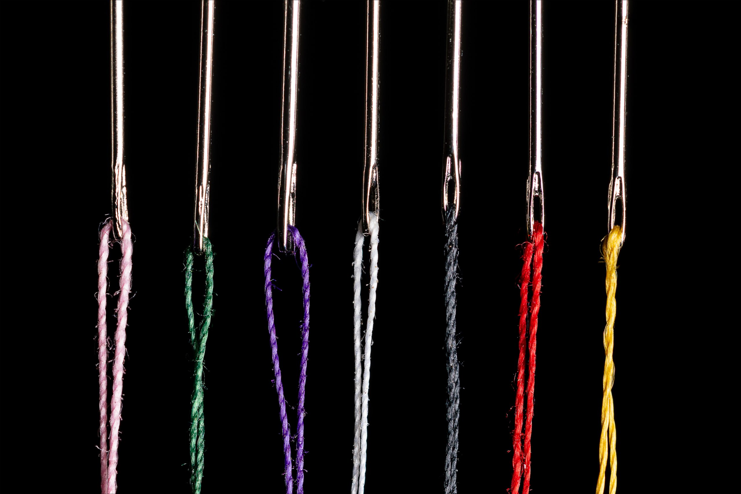 sewing needles each with a different color thread