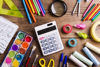 Desk with school supplies. Studio shot on wooden background.