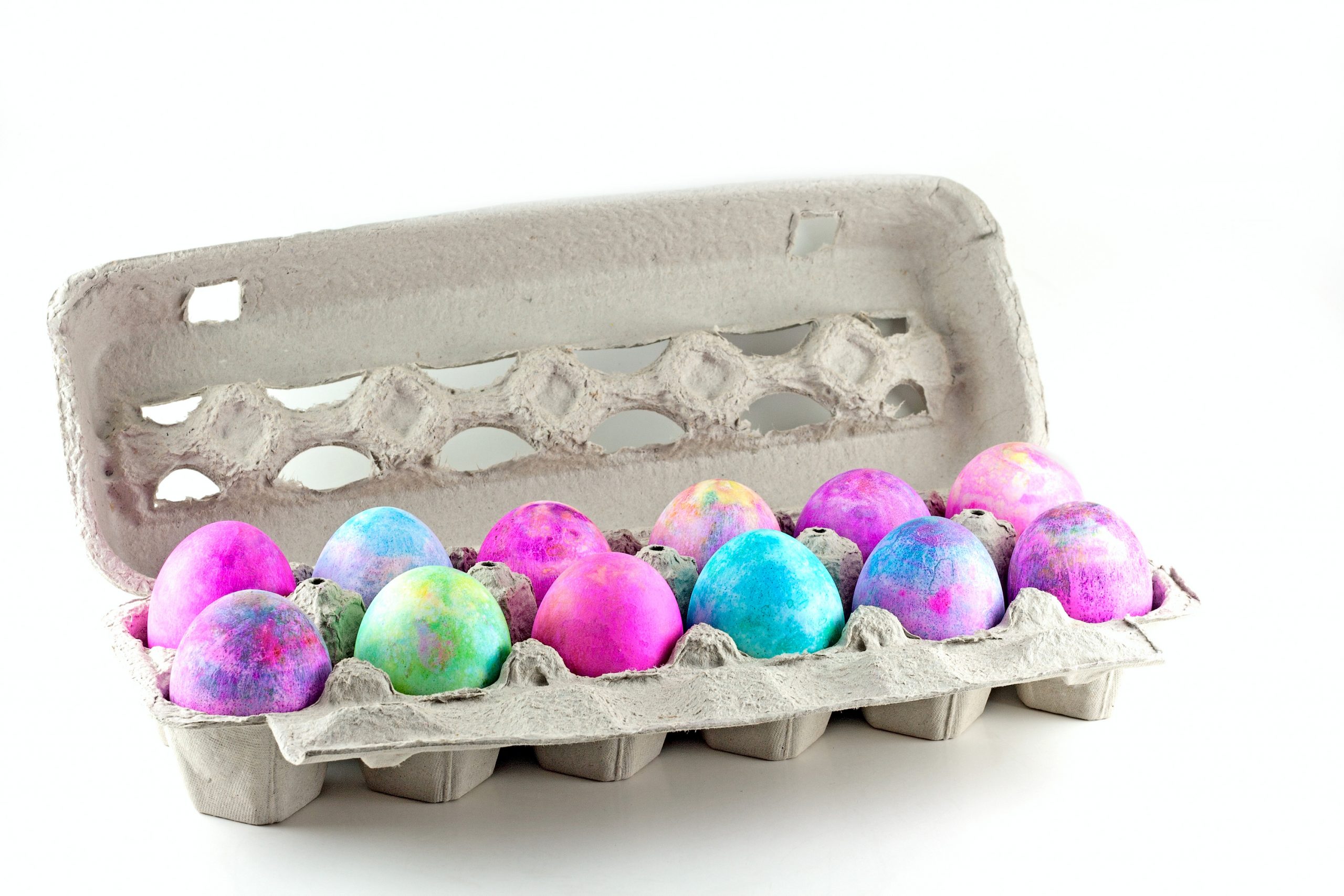 A carton full of shaving cream Easter eggs. The eggs have a multi-colored look.