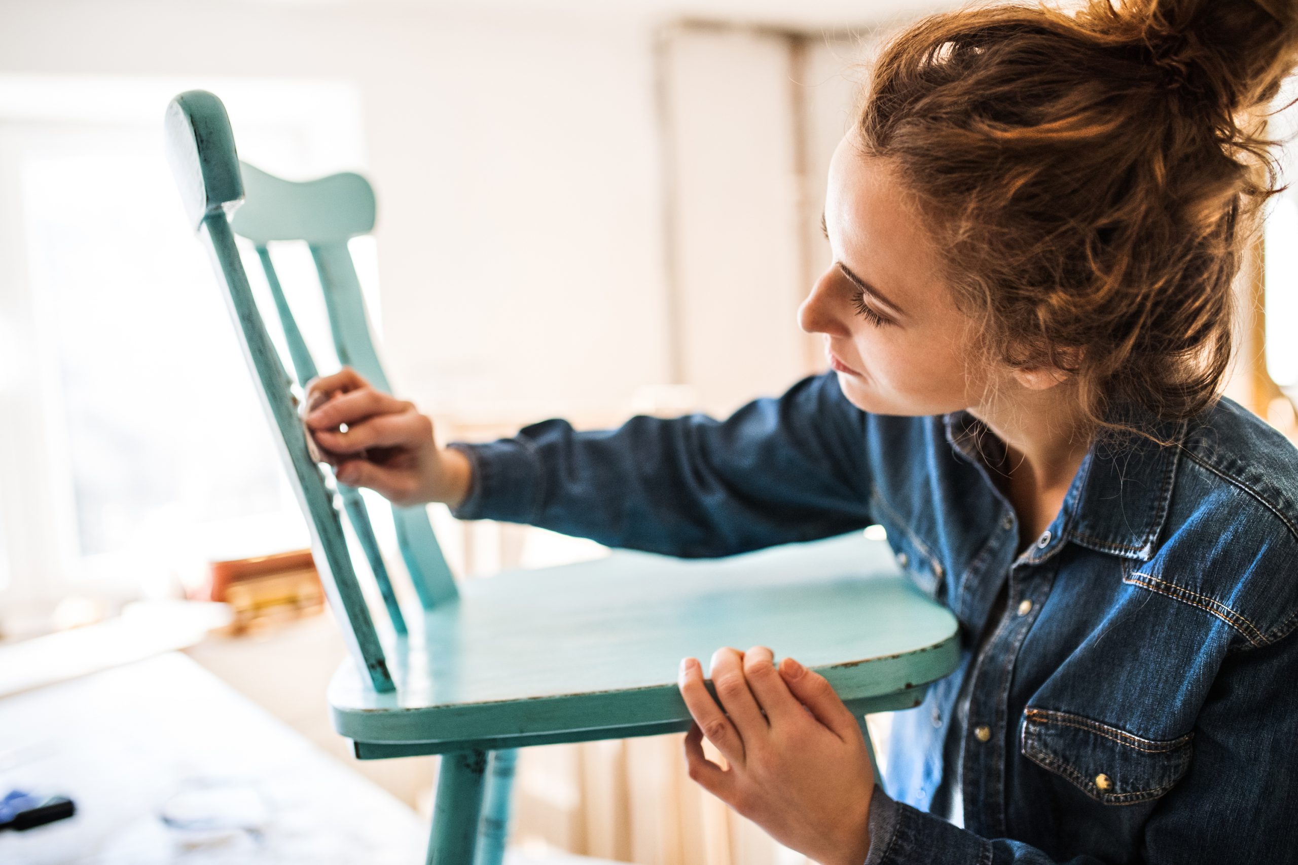 Sanding a wood chair. This is the first step for preparing to spray paint wood furniture.