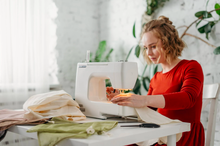 A woman in red stitching on a serger.